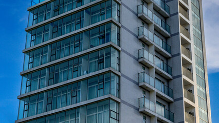 Fototapeta premium Modern high-rise building with glass balconies against blue sky