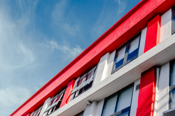 Modern red and white building against blue sky with cloud streaks