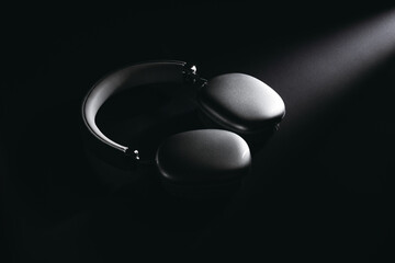 Sleek black wireless headphones on dark background with dramatic lighting