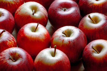 Close-up of fresh red apples with stems on a wooden surface
