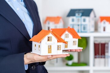 Real Estate Agent Holding Miniature House Model – Property Investment Concept