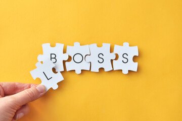 Concept of boss and loss, leadership and failure word puzzle on yellow background
