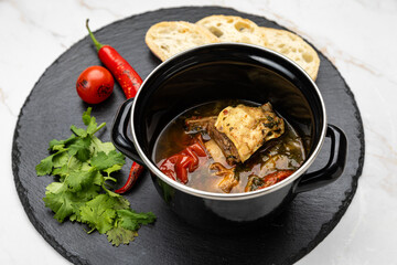 Traditional Georgian khashlama stew with beef, vegetables, herbs and bread on slate plate
