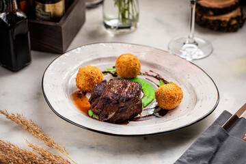 Tender grilled beef filet with crispy potato croquettes and green pea puree, served with demi-glace sauce