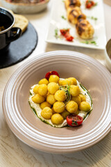 Gourmet potato balls with creamy sauce, herbs and cherry tomatoes on ceramic plate