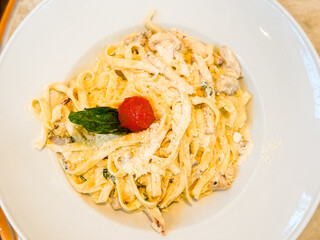 Plate of pasta with parmesan, mushroom, and cherry tomato garnish. Cuisine, nutrition, and lifestyle moments in restaurant dining culture.