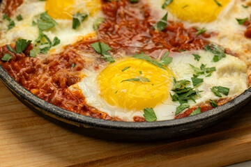 Shakshuka in cast iron skillet with tomatoes, herbs, and sunny-side-up eggs