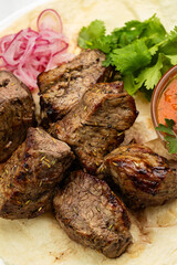 Traditional Georgian grilled meat (mtsvadi) with onion, herbs, and sauce on lavash