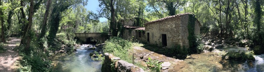 Tranquil stone building nestled beside a babbling brook, surrounded by lush green forest.