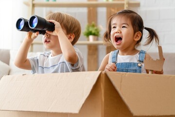 Playful Children Imagining Adventures with Binoculars and a Cardboard Boat