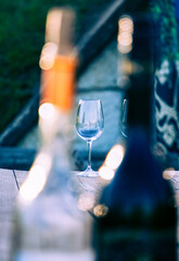 empty wine glass seen through bottles