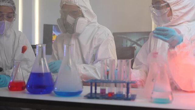 A team of medical researchers in full protective suits examines a chemical compound. They are working together in a high security lab to develop a new vaccine for a global pandemic.