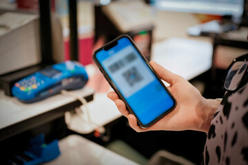 Hand Holding Mobile Phone Displaying QR Code for Payment