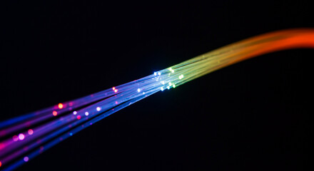 Colorful optical fibers glowing brightly against a dark background.