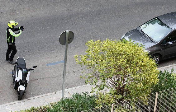 Agente de estacionamiento regulado motorista haciendo foto con c&aacute;mara y multando a coche mal aparcado en zona ser azul