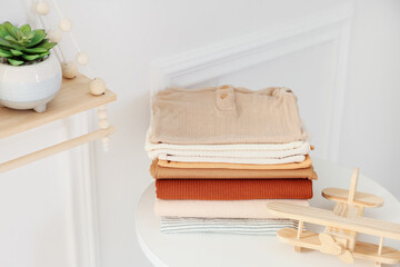 Stack of clean baby clothes and toy on white table indoors, space for text
