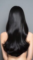 Naklejka premium Back view of a person with long, sleek, dark hair styled in soft waves against a gray background, showcasing shine and smooth texture