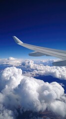 Obraz premium Airplane wing cuts through a vibrant, deep blue sky, contrasting sharply with the puffy white clouds below, creating a dreamy aerial perspective