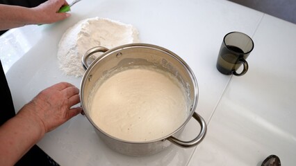 Chef whisking ingredients in metal bowl on white table