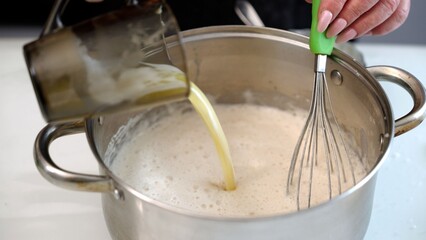 Chef whisking ingredients in stainless steel pot