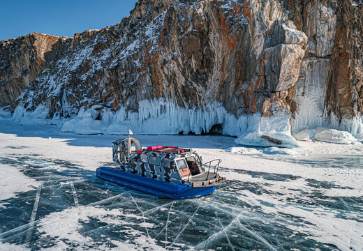 Hovercraft parked on a blue cracked ice of the lake Baikal. Tourists transportation and entertainment on winter Baikal.