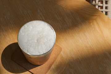 a glass of iced milk coffee on wooden table in sun light and shade