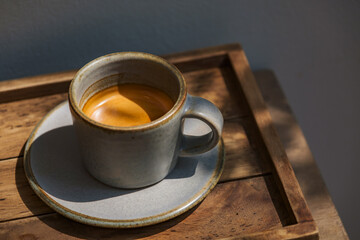 espresso coffee shot serving in small mug on wooden table in sun light and shade of wood branches and leaves