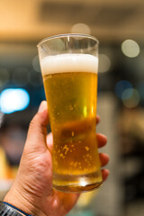 Hand holding cool beer mug, foam on top of beer glass