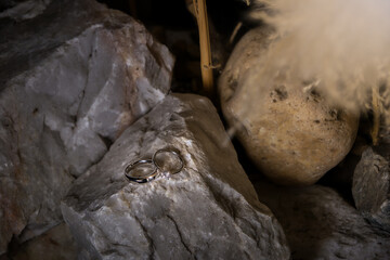 couple of rings put on the natural rock in soft spot light and shade