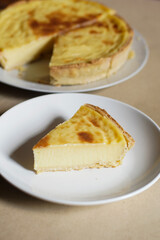 A warm, appetizing slice of French custard tart (flan patisserie) on a white plate