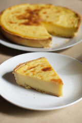 Custard Tart Slice on White Plate with Whole Tart in Background