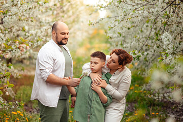 Happy family mom dad and teenager boy having fun on a spring walk in a blooming park