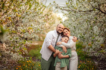 Happy family mom dad and teenager boy having fun on a spring walk in a blooming park