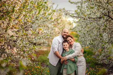 Happy family mom dad and teenager boy having fun on a spring walk in a blooming park