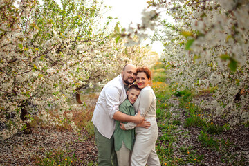 Happy family mom dad and teenager boy having fun on a spring walk in a blooming park