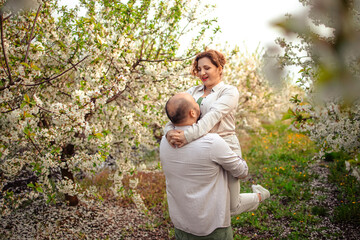 happy couple of adults on a walk in the spring park. family leisure. husband and wife walking in nature