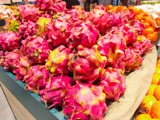 Fresh dragon fruits stacked on display at a market. Vibrant pink skin with green scales, tropical exotic fruit rich in nutrients, perfect for juice, smoothies, or desserts.