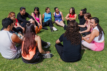 Group portrait of Latin people sitting in a circle on the grass outdoors in Mexico, Latin America. Large and diverse group of Hispanic people of different ages