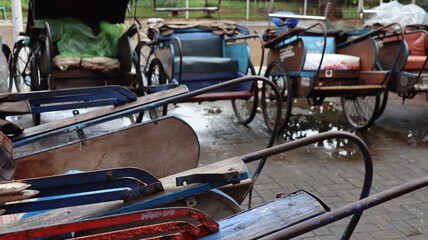 Row of colorful traditional pedicabs with vintage bicycle design parked near orange wall in urban street
