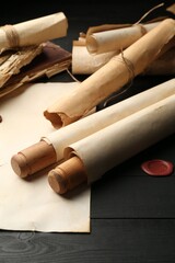 Many old rolled scrolls on black wooden table, closeup