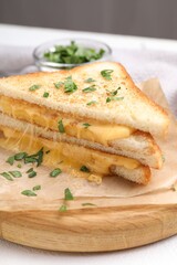 Delicious sandwiches with melted cheese and parsley on white table, closeup