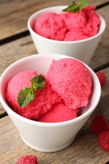 Delicious raspberry sorbet with mint in bowls and fresh berries on wooden table, closeup