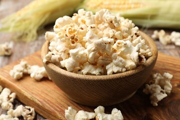 Tasty popcorn and corncobs on wooden table, closeup