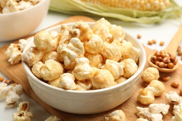 Tasty popcorn, corncob and corn kernels on white table, closeup