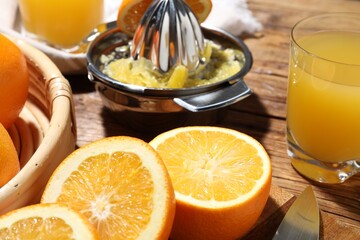 Freshly squeezed orange juice, fruits and juicer on wooden table, closeup