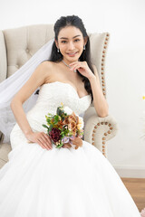 Asian Bride wedding dress bouquet veil smiling jewelry sitting chair indoor elegant beauty celebration happiness portrait female gown lace flower formal event ceremony fashion luxury happiness