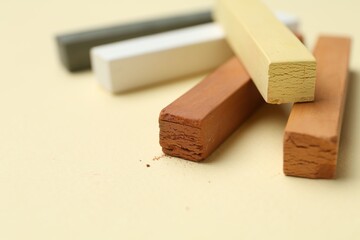 Many colorful chalk pastels on beige background, closeup. Space for text