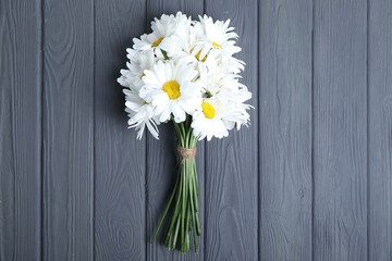 Obraz premium Bouquet of beautiful chamomile flowers on grey wooden table, top view