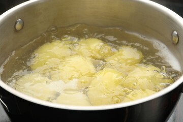 Young potatoes boiling in pot on stove, closeup