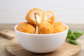 Delicious fried croquettes in bowl and basil on table, closeup